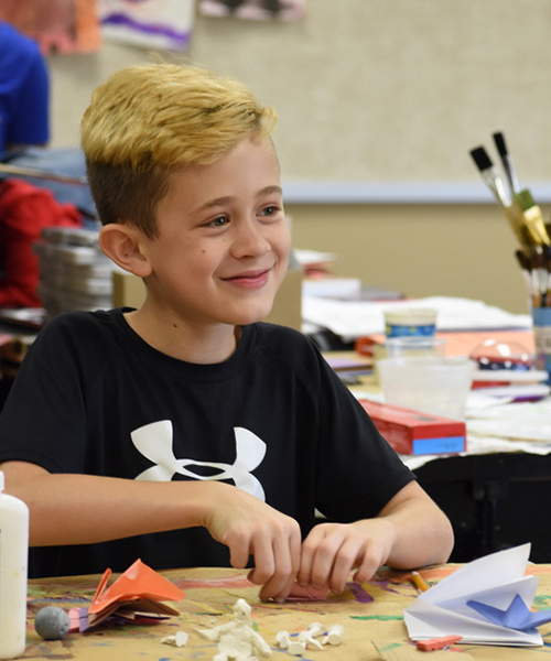 Happy kid making paper toys